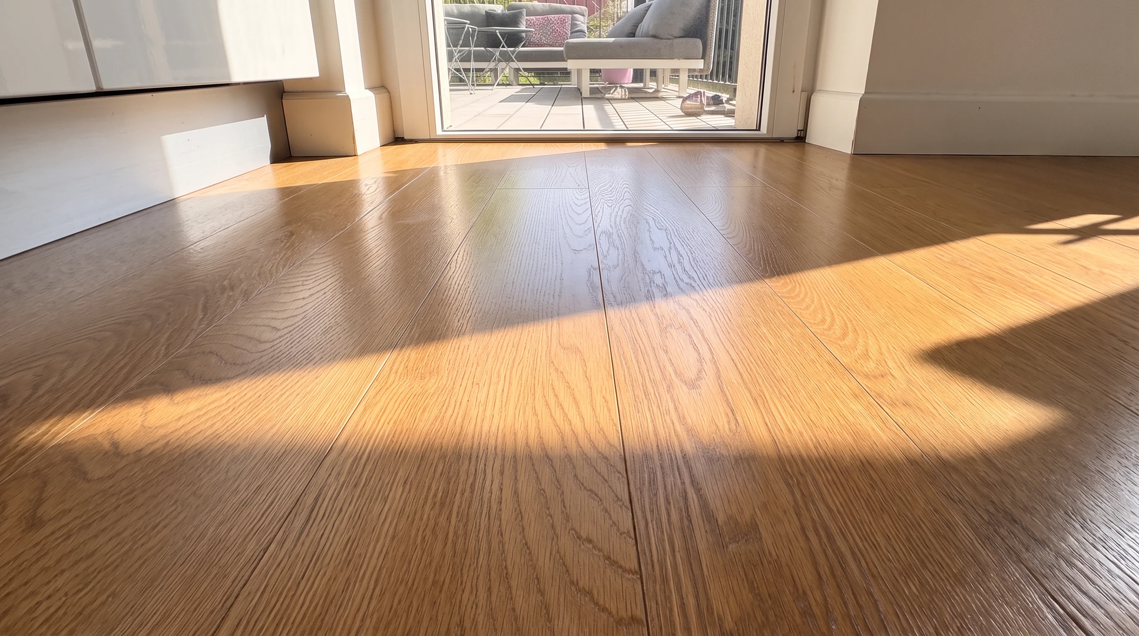 Travailleur en train de poser du carrelage sur sol intérieur, à genoux, portant des gants de protection jaunes et bleus